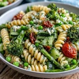 Colorful spring garden pasta salad with crisp broccoli, sweet peas, and cherry tomatoes, perfect for picnics or light lunches.