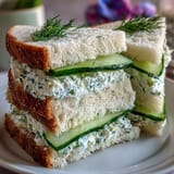 Delicate cucumber tea sandwiches with herbed cream cheese on soft white bread, perfect for afternoon tea or elegant gatherings. Crisp cucumber slices and fresh herbs add a refreshing flavor to these classic finger sandwiches.