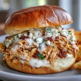 Juicy, tender smoked chicken tossed in zesty white BBQ sauce, served on toasted buns with crunchy coleslaw for a Southern-style sandwich.  