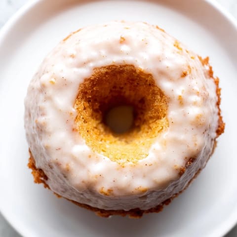 Warm, freshly baked muffin tin donuts covered in sweet, creamy glaze, ready to enjoy.