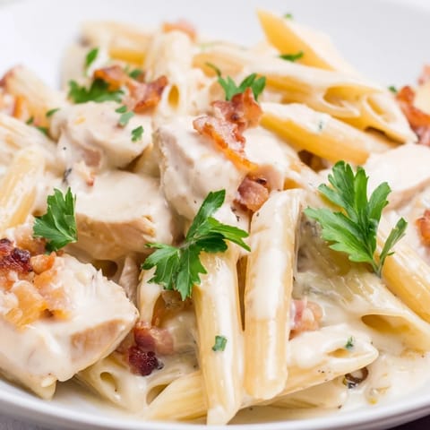 Fresh parsley garnish enhances this hearty Creamy Chicken Bacon Penne served alongside a crisp green salad and crusty bread.