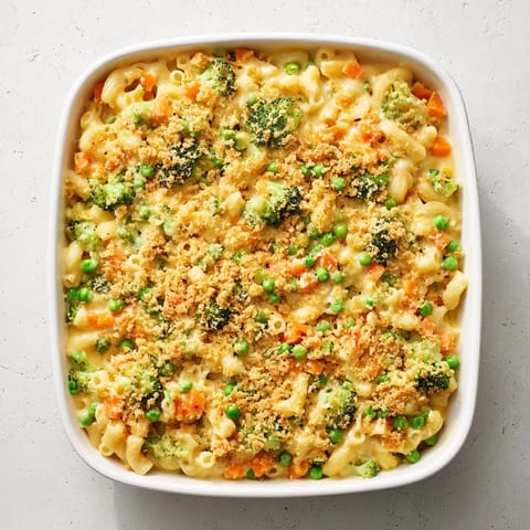 A serving of Garden Veg Mac and Cheese on a white plate, creamy cheddar sauce clinging to elbow pasta and vibrant vegetable pieces.