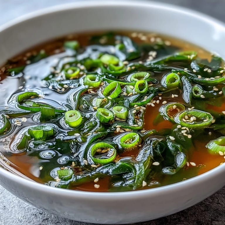A warm bowl of savory Wakame Soup garnished with fresh scallions, served alongside fluffy steamed rice.