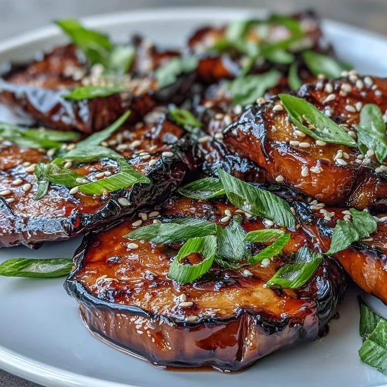 Close-up of tender, caramelized Miso Glazed Eggplant with a glossy miso sauce and fresh green onion topping.  