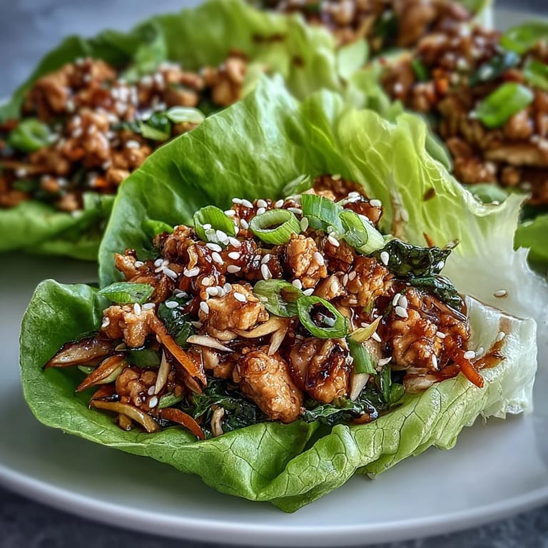 Savory ground turkey potsticker stir-fry lettuce wraps filled with crisp Napa cabbage, carrots, and shiitake mushrooms on a plate.