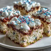 Red, white, and blue Rice Krispies treats stacked in patriotic layers, perfect for a festive 4th of July dessert table.